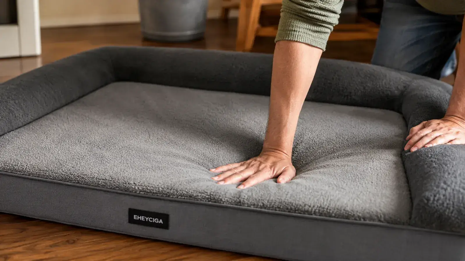 Person pressing their palm into the surface of an orthopedic dog bed to test foam density